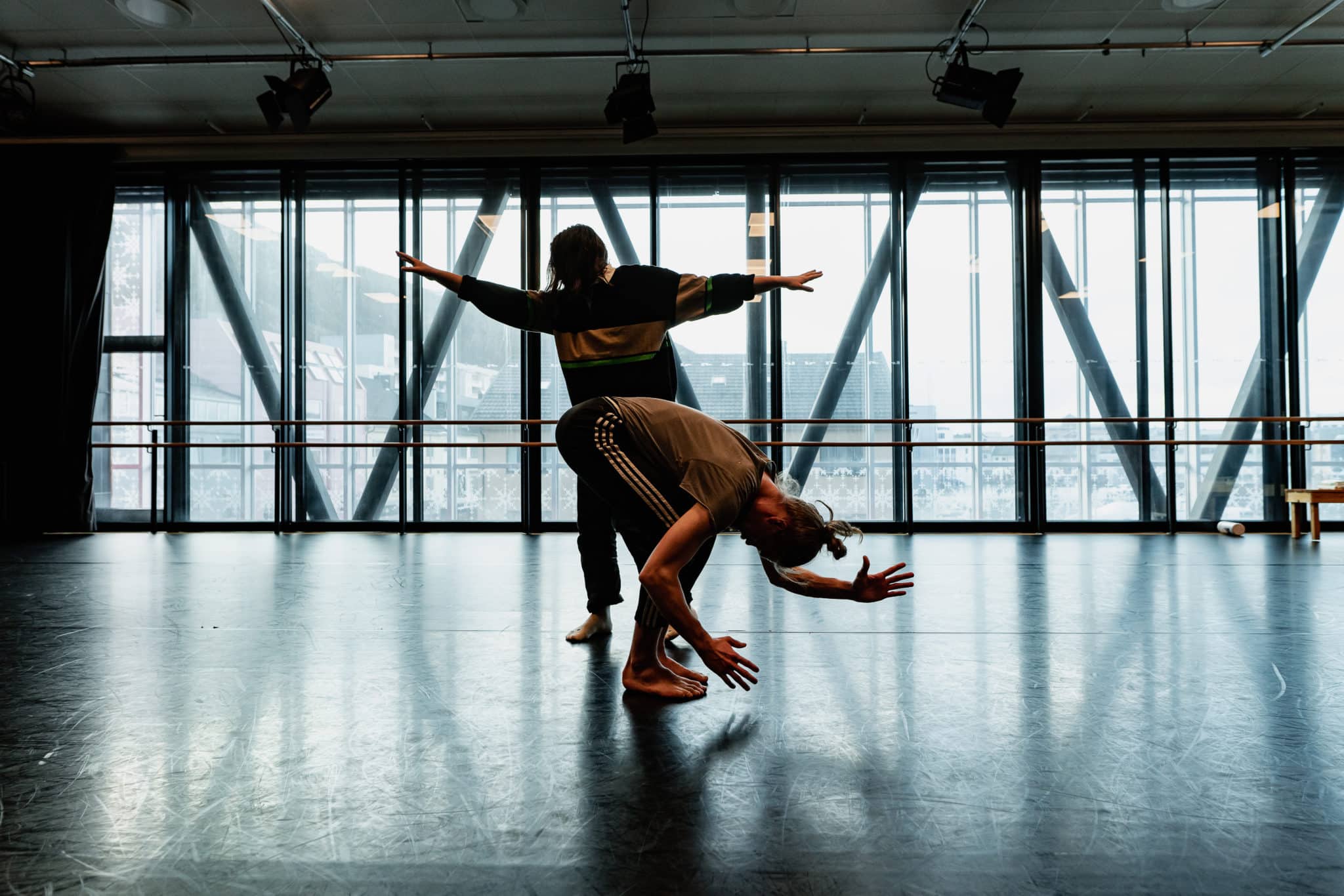 Two performing artists are training in a room with a glass wall.