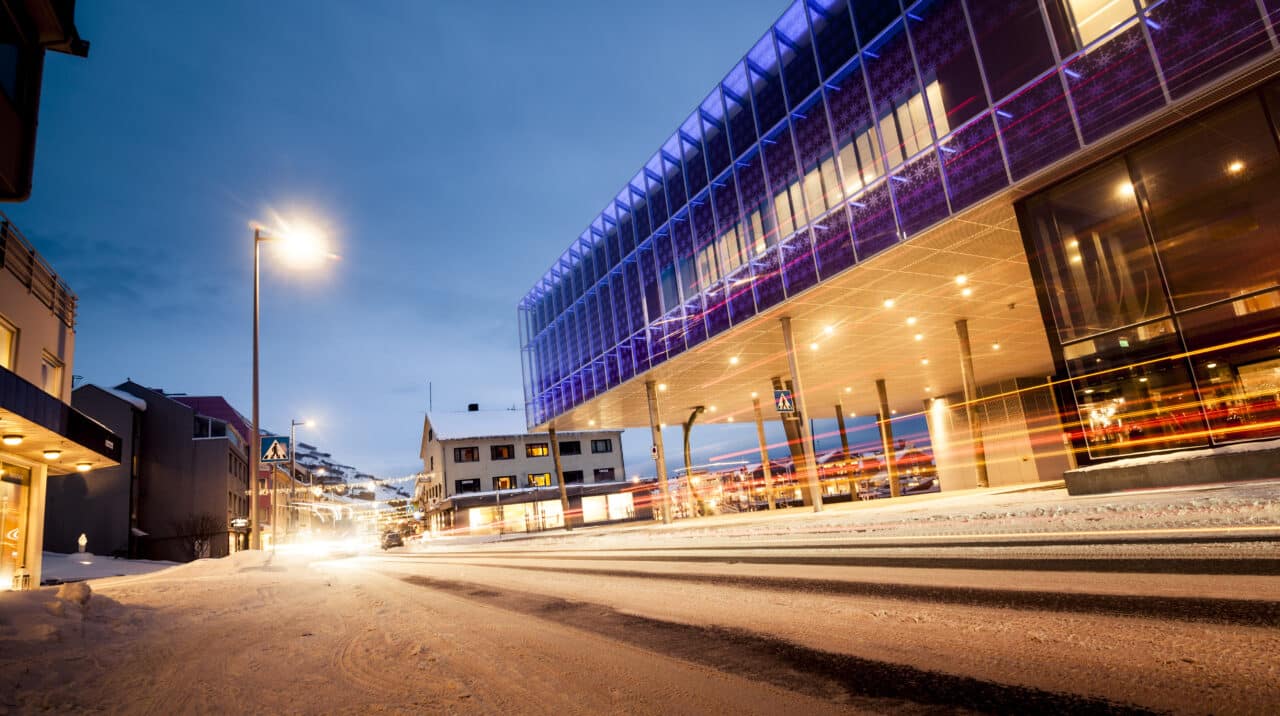 Bild på en snötäckt gata i Hammerfest under mörkertiden, tagen utanför Davvi – Senter for scenekunst.