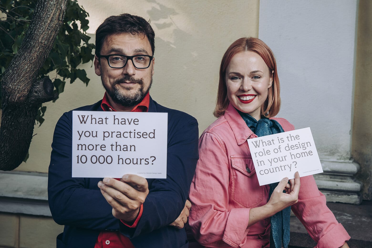 Two people sitting holding question cards.