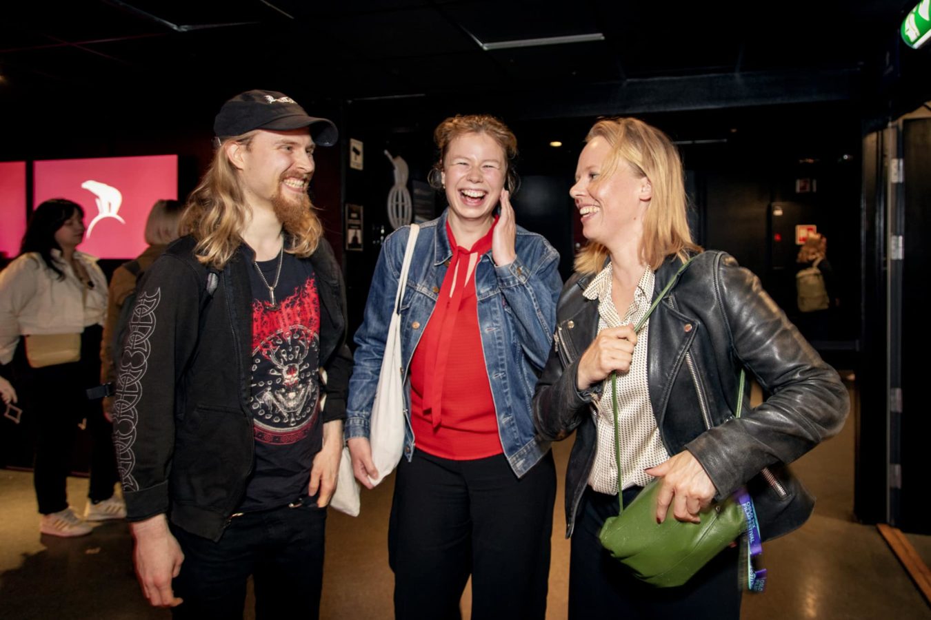 Three people are standing in front of the camera laughing at each other.