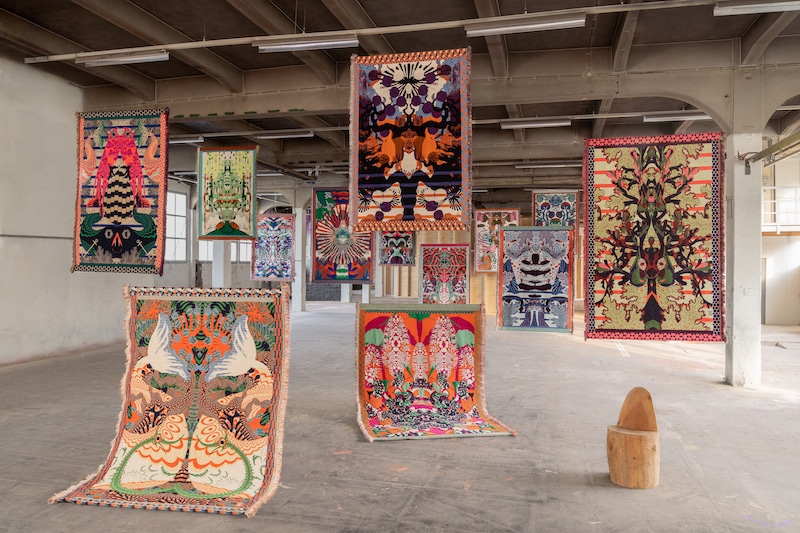 Colorful textile art hanging from the ceiling in an exhibition room.