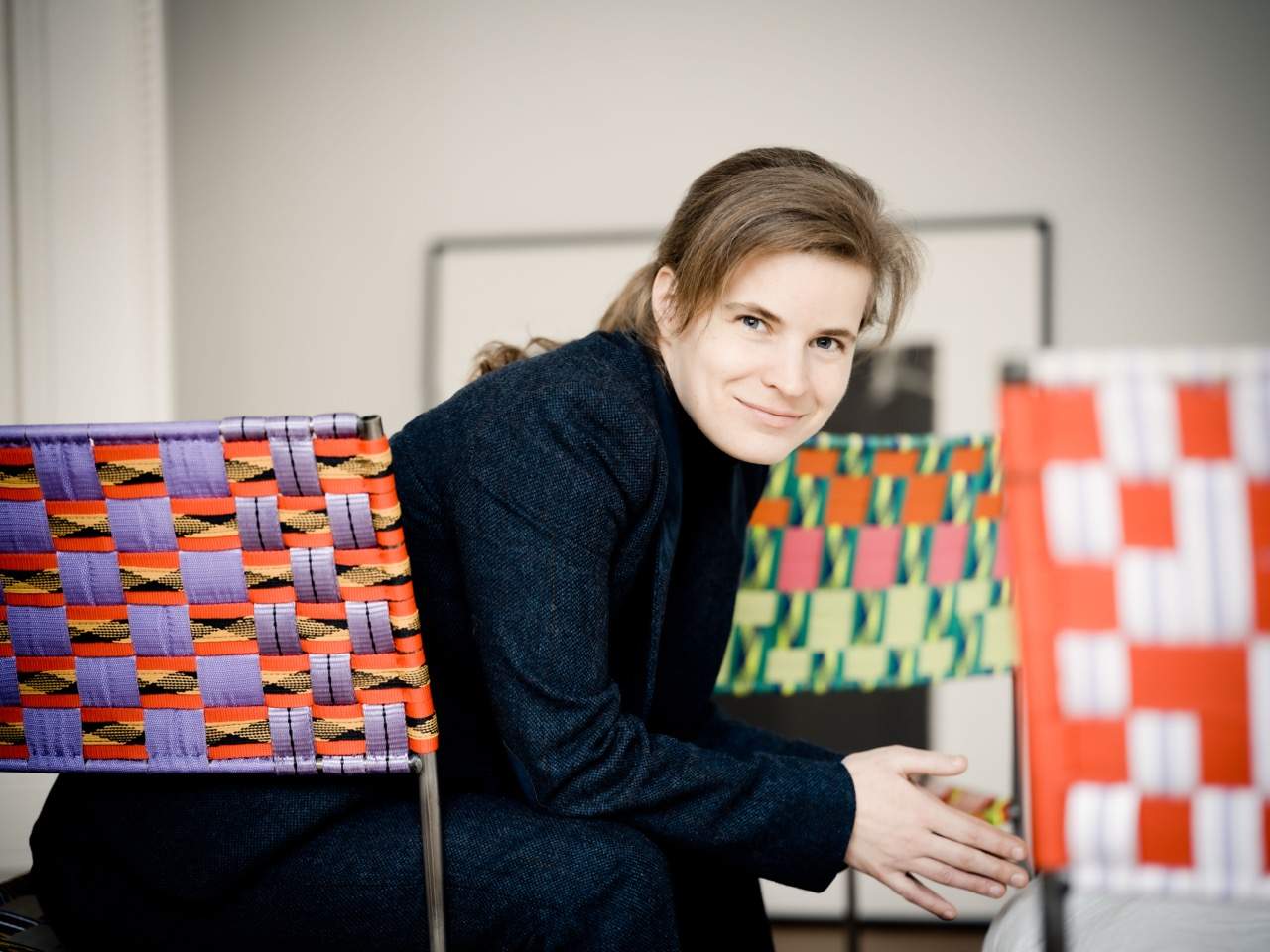 A woman sitting on a chair against a colourful bakcground.