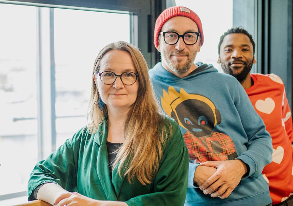 A photo of a woman and two men standing next to each other.