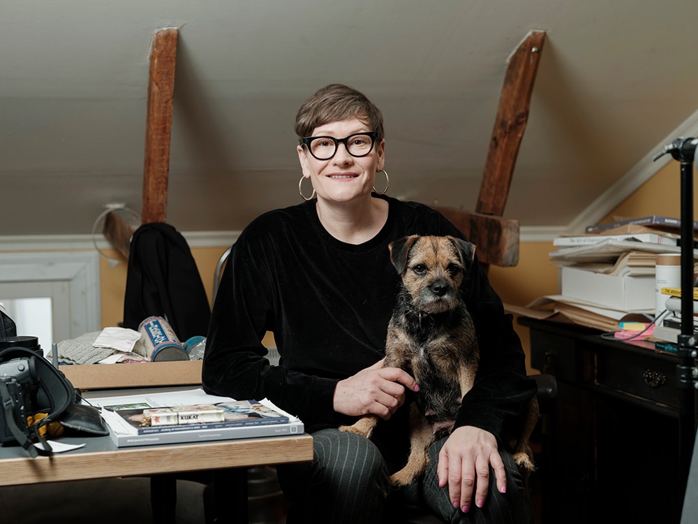 Artist Kati Leinonen sitting in the studio with a dog.
